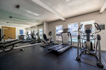 A gym with cardio machines and weights on the floor